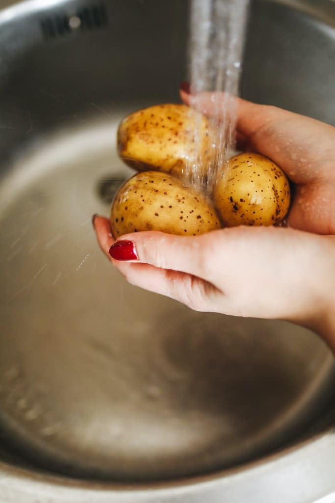 cleaning potatoes in the sink with water