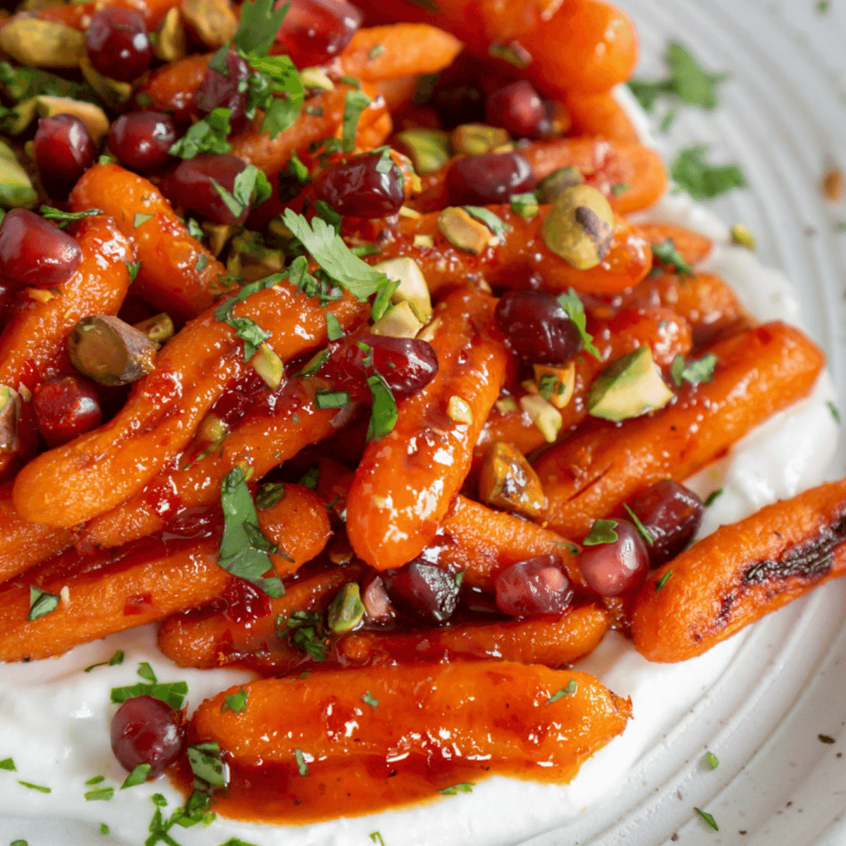 Harissa honey roasted carrots on a plate with whipped feta and pistachios.