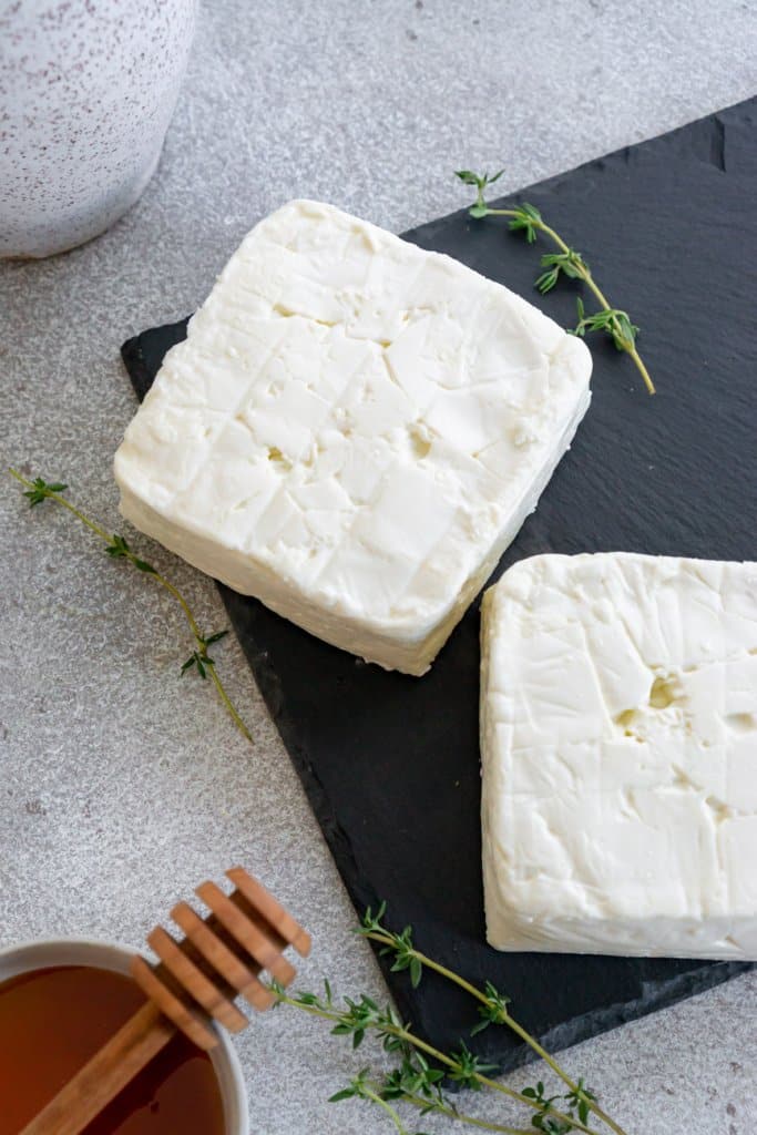 two blocks of feta cheese with honey in a bowl