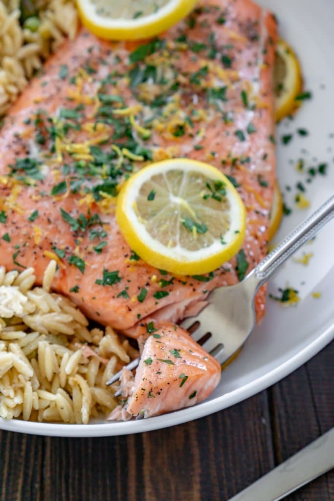lemon pepper salmon on a white plate with a bite on a fork