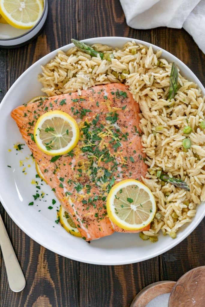 lemon pepper salmon with lemon slices on top with goat cheese orzo