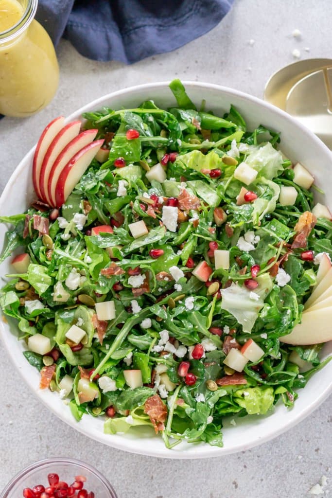 pomegranate salad in a white salad bowl with dressing to the side