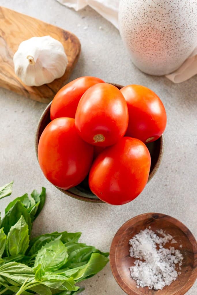 roma tomatoes, basil, salt, and garlic in small ingredient bowls