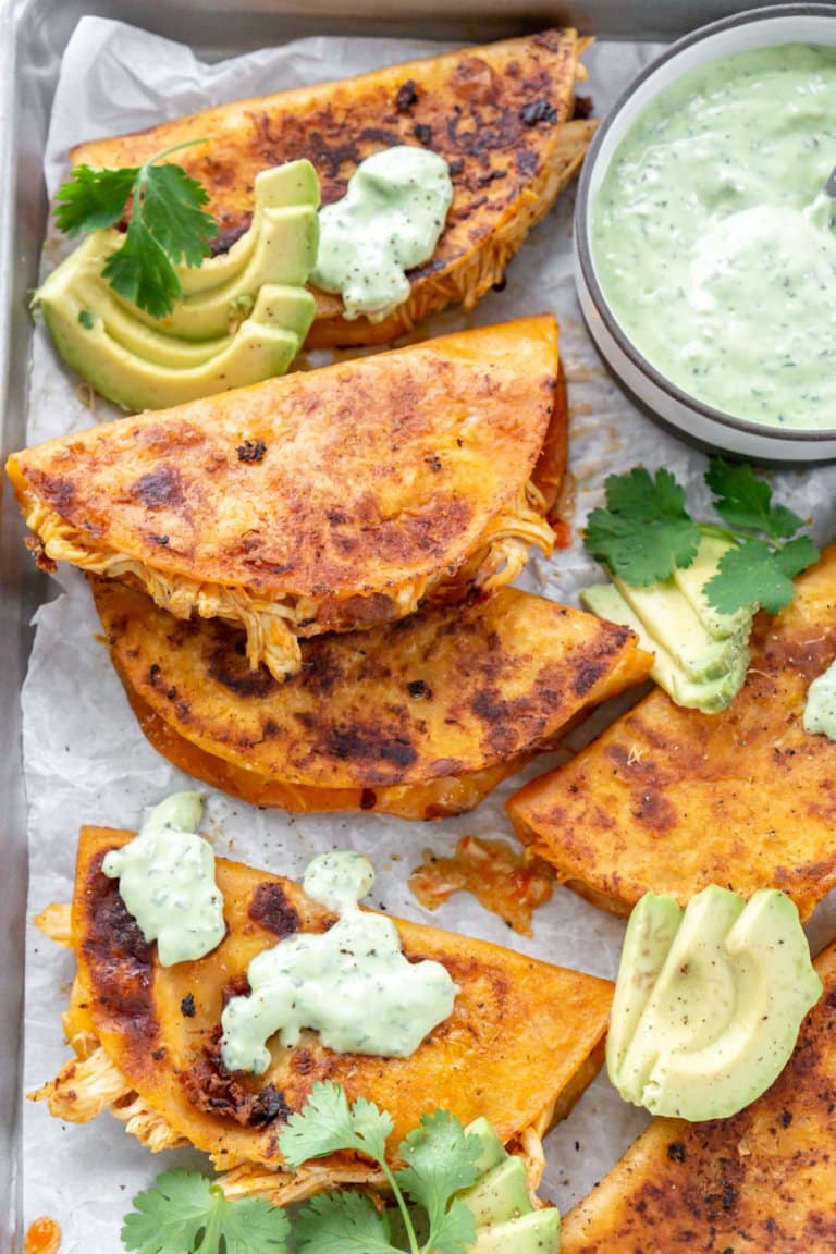 buffalo chicken tacos on a sheet pan with jalapeno sauce and sliced avocado