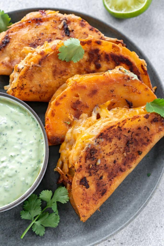 buffalo chicken tacos on a plate with creamy jalapeno sauce in a small bowl