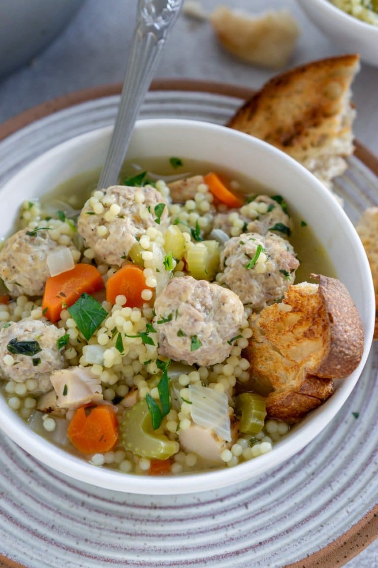 chickarina soup in a white bowl with toasted bread to the side