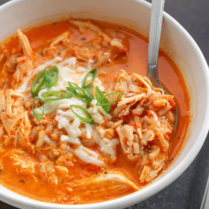 roasted red pepper soup in a white bowl with a spoon