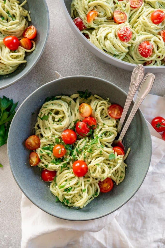 two bowls and a pot of avocado pasta