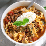 one pot lasagna soup in a white bowl with ricotta cheese on top