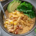 chicken taco soup in a bowl with a spoon and sliced avocado and cilantro