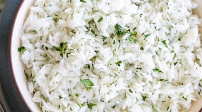 a bowl of ginger rice on a grey plate with a serving spoon