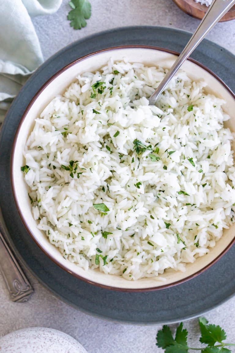 a bowl of ginger rice on a grey plate with a serving spoon