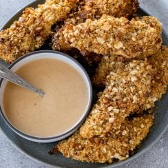 pretzel crusted chicken tenders on a plate with sauce