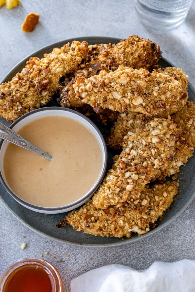 pretzel crusted chicken tenders on a plate with sauce