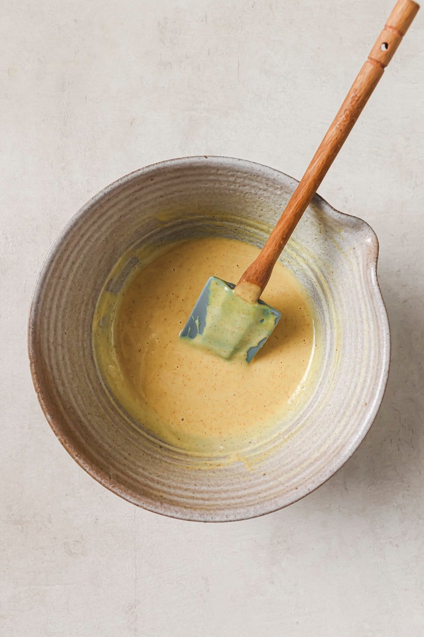 homemade honey mustard in a mixing bowl with a spatula.