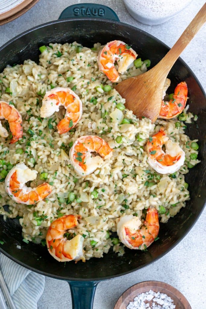 shrimp asparagus risotto in a skillet with a wooden spoon