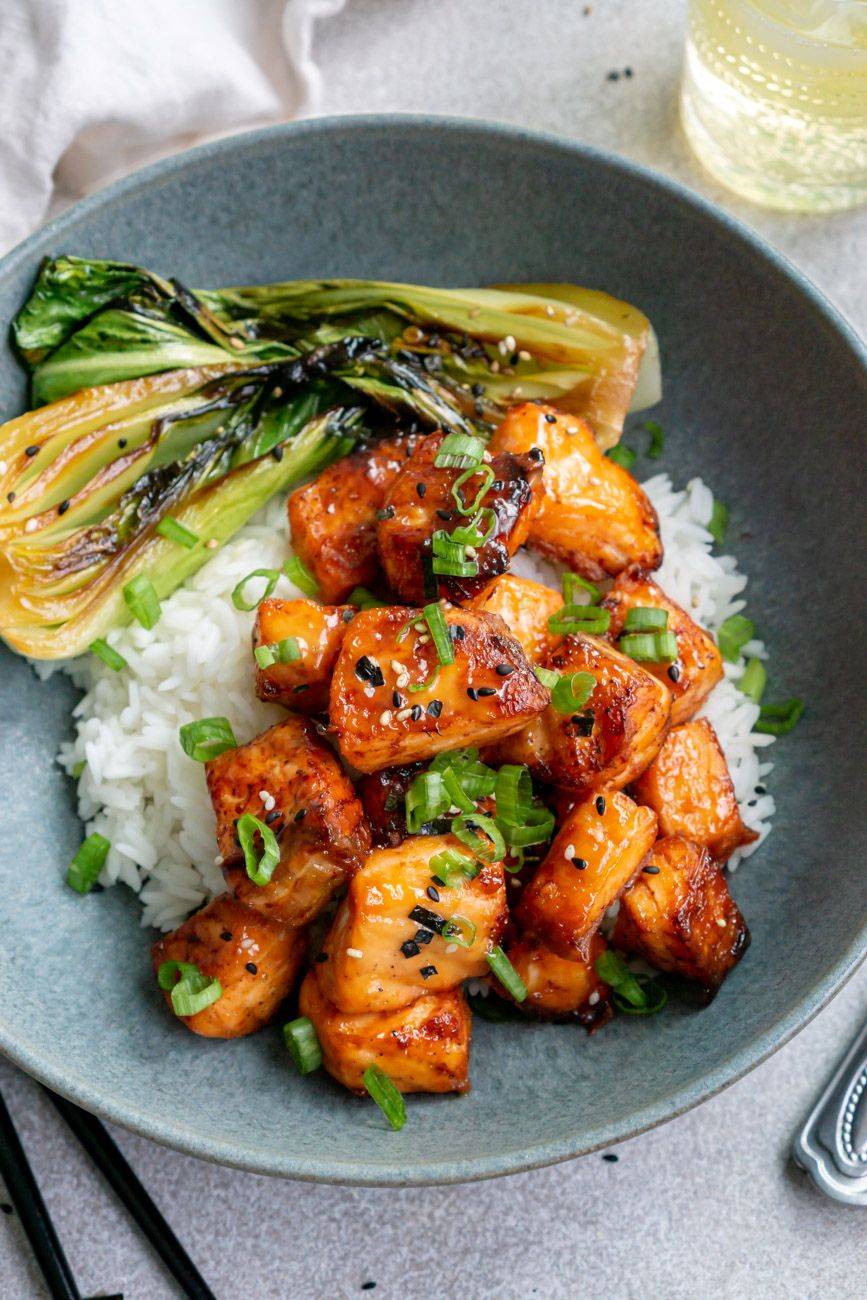 Miso salmon bites over rice with bok choy in a ceramic dish.