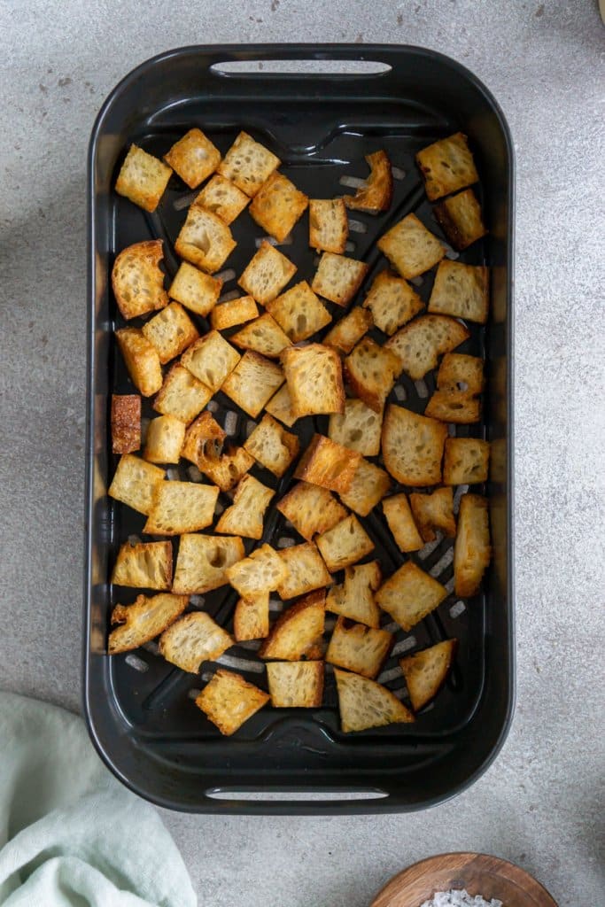 air fryer croutons in a single layer in an air fryer basket.