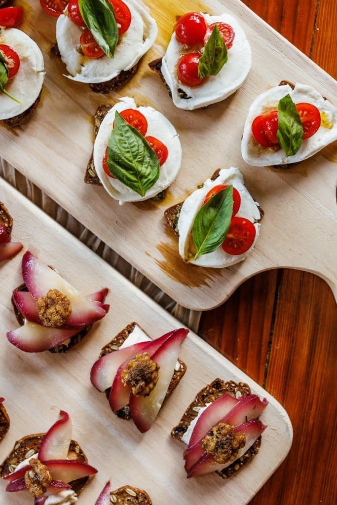 cheese, tomato, and basil crackers on a plate.