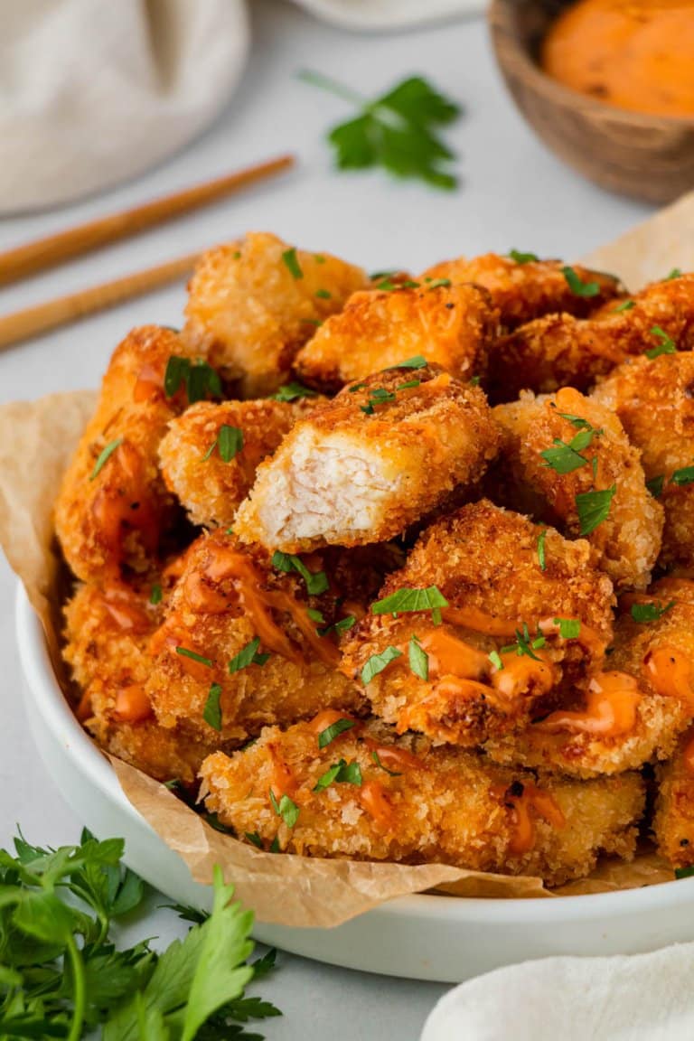 bang bang chicken in a bowl, one with a bite taken out of it and parsley to the side