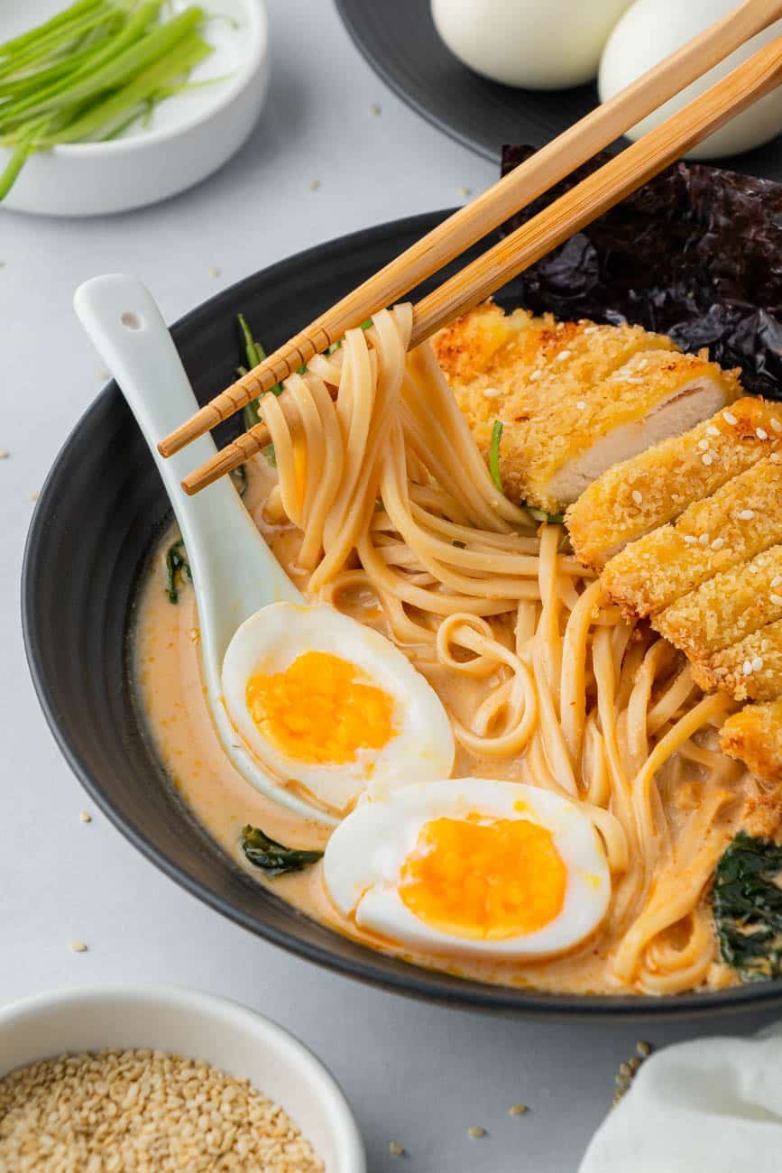 Chopsticks lifting ramen noodles out of the bowl.