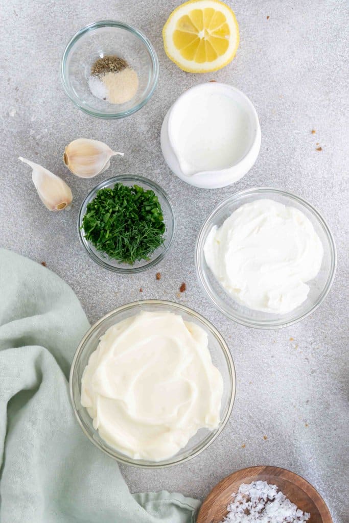 mayonnaise, sour cream, buttermilk, fresh herbs, lemon, and garlic in small ingredient bowls