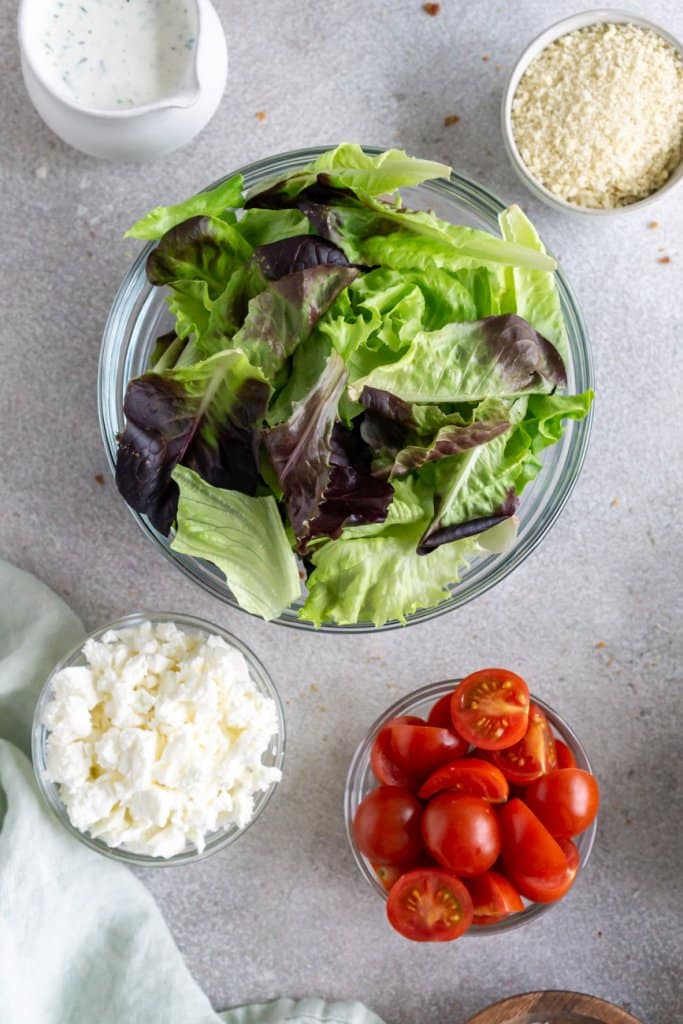 little gems lettuce, tomatoes, feta cheese, panko breadcrumbs, and ranch dressing in small bowls.