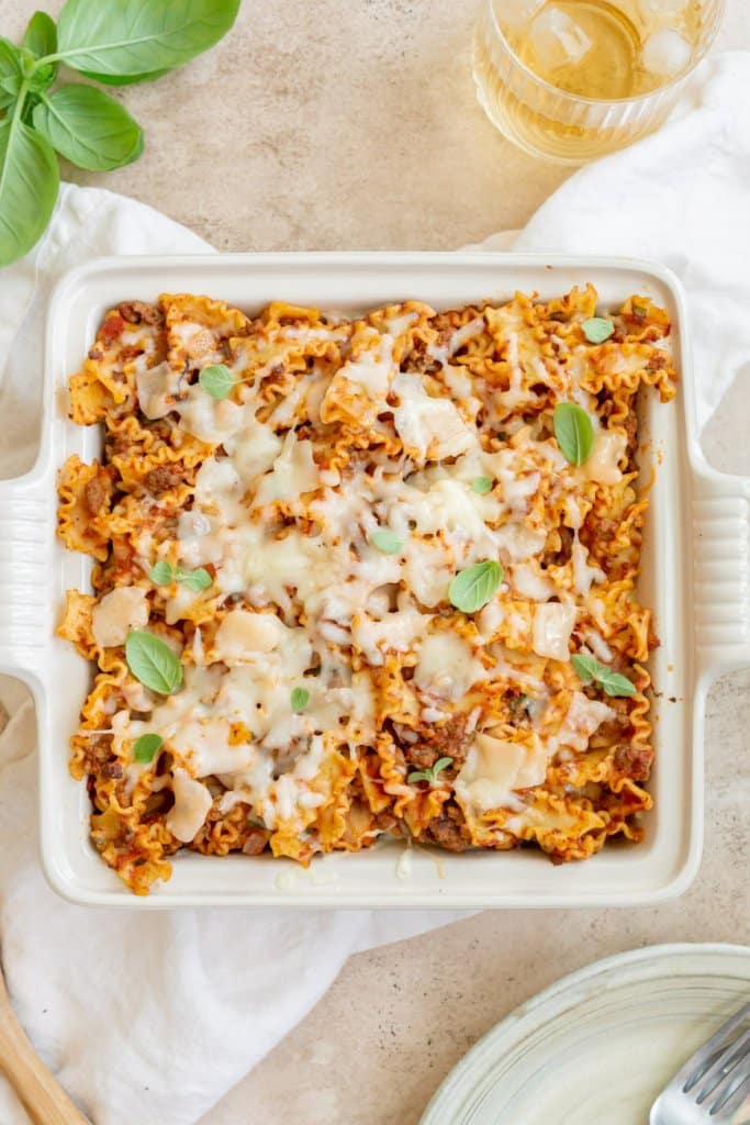 lazy lasagna casserole with a glass of sparkling water and a plate with a fork on the side