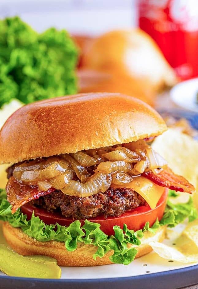 close up of bacon cheeseburger with lettuce, tomato and Coca Cola onions in brioche bun