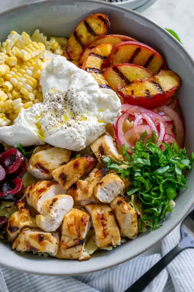 close up of grilled chicken pasta salad with grilled peaches, corn and onions