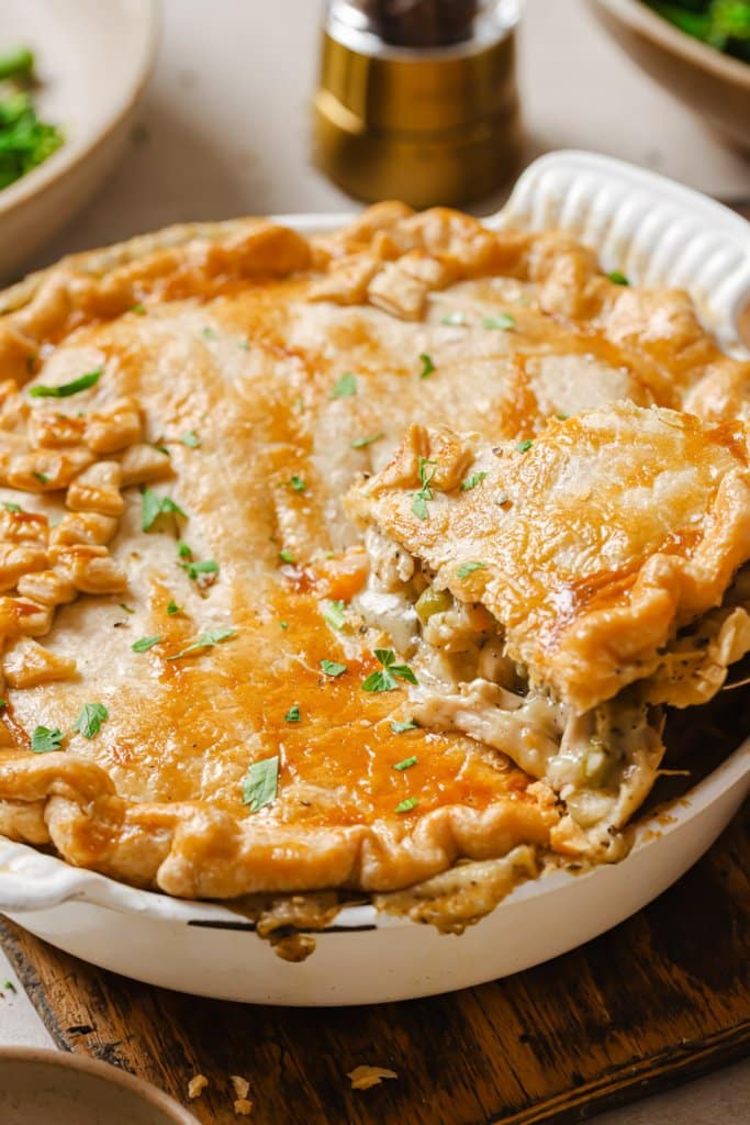 thanksgiving leftover pot pie in a white pie dish and lifting a piece out