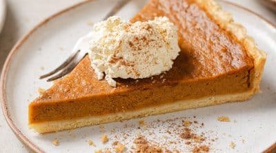 a piece of sweet potato pie on a plate with whipped cream on top and a fork