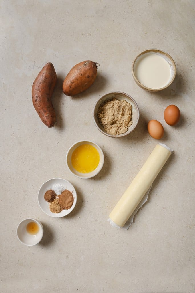 sweet potatoes, butter, spices, pie crust, heavy cream, eggs, and sugar in small ingredient bowls