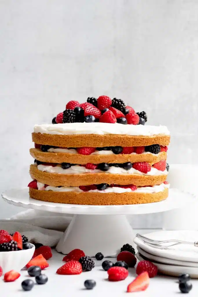 vanilla cake with berry and buttercream layers on a white cake stand