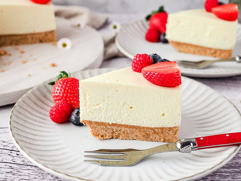 slice of cheesecake with berries on white plate with silver fork