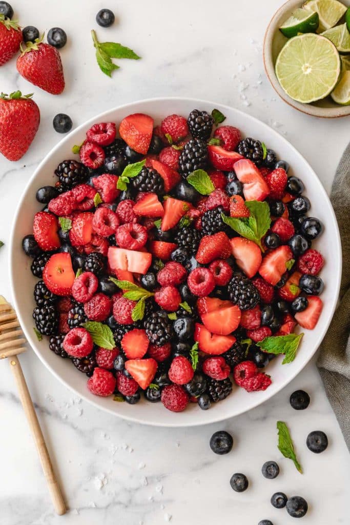 overhead view of summer berry salad with mint in white serving dish