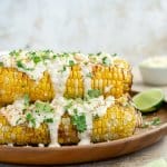 air fryer corn on the cob on a plate with mexican street corn toppings