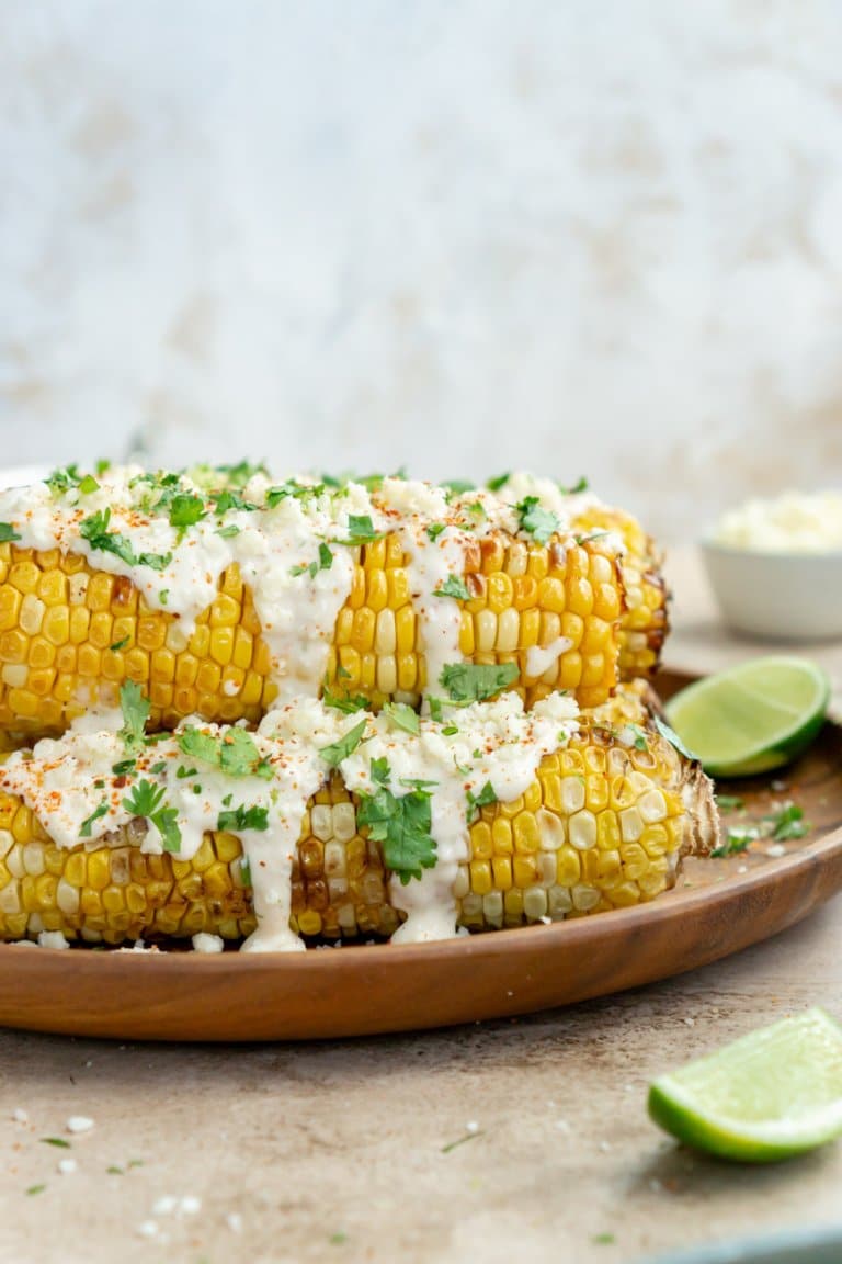 air fryer corn on the cob on a plate with mexican street corn toppings