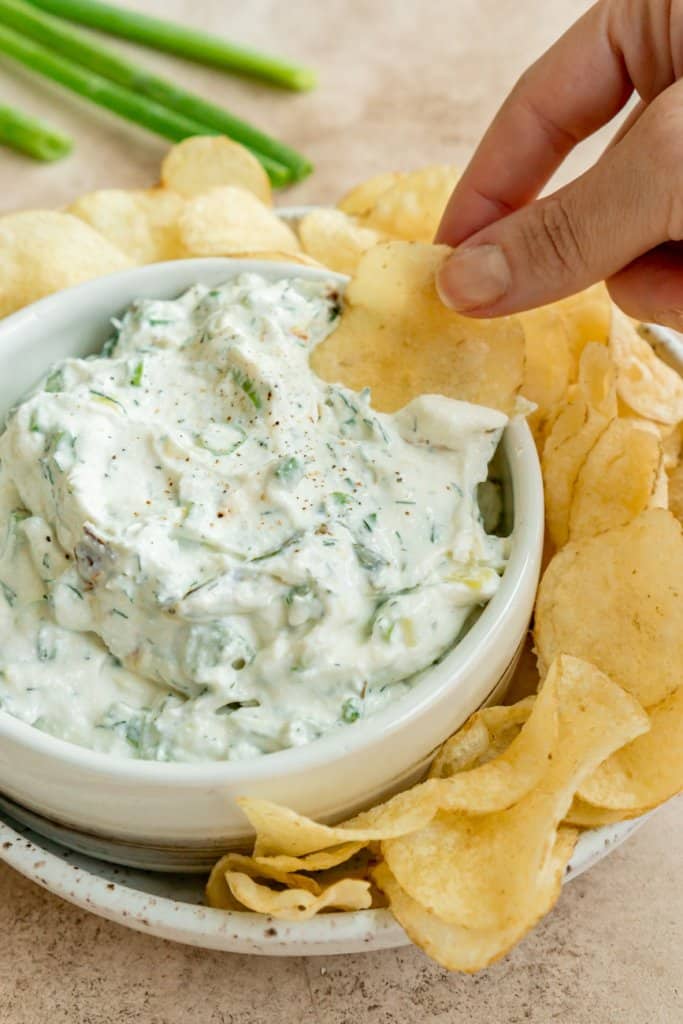 a hand dipping a chip into whipped cottage cheese dip
