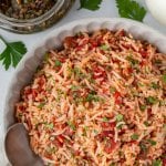 chimichurri rice in a bowl with a spoon and chimichurri sauce on the side