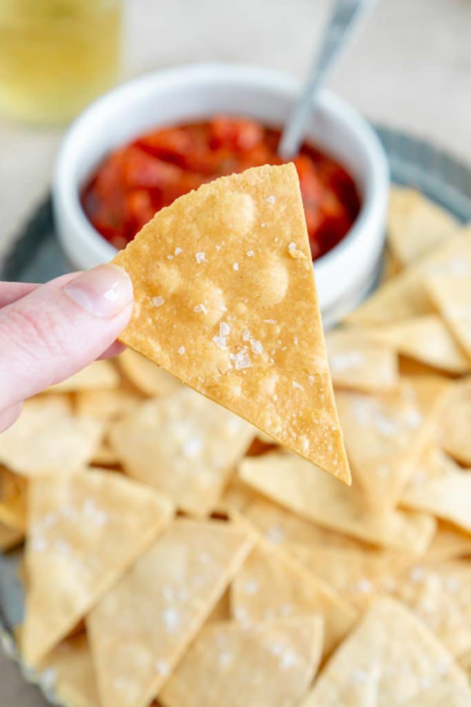 close up of a hand holding an air fryer tortilla chip