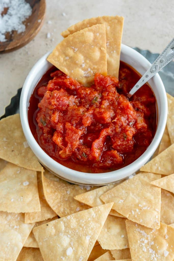 air fryer tortilla chips in a bowl of salsa with a small spoon