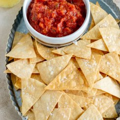 air fryer tortilla chips on a serving platter with salsa in a small bowl