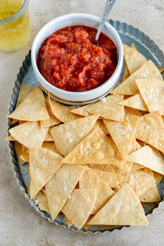 air fryer tortilla chips on a serving platter with salsa in a small bowl