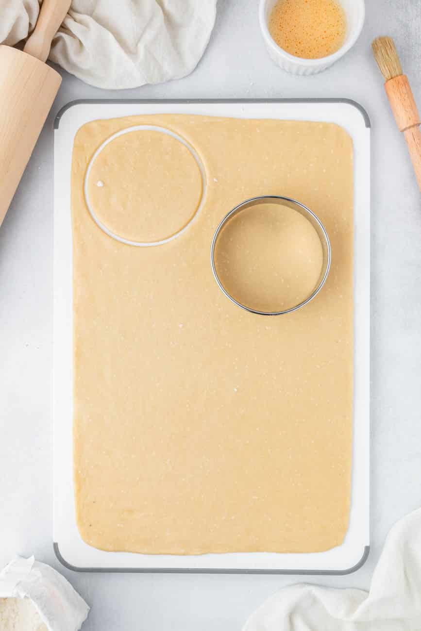 Cookie cutter cutting a circle in pie crust dough.