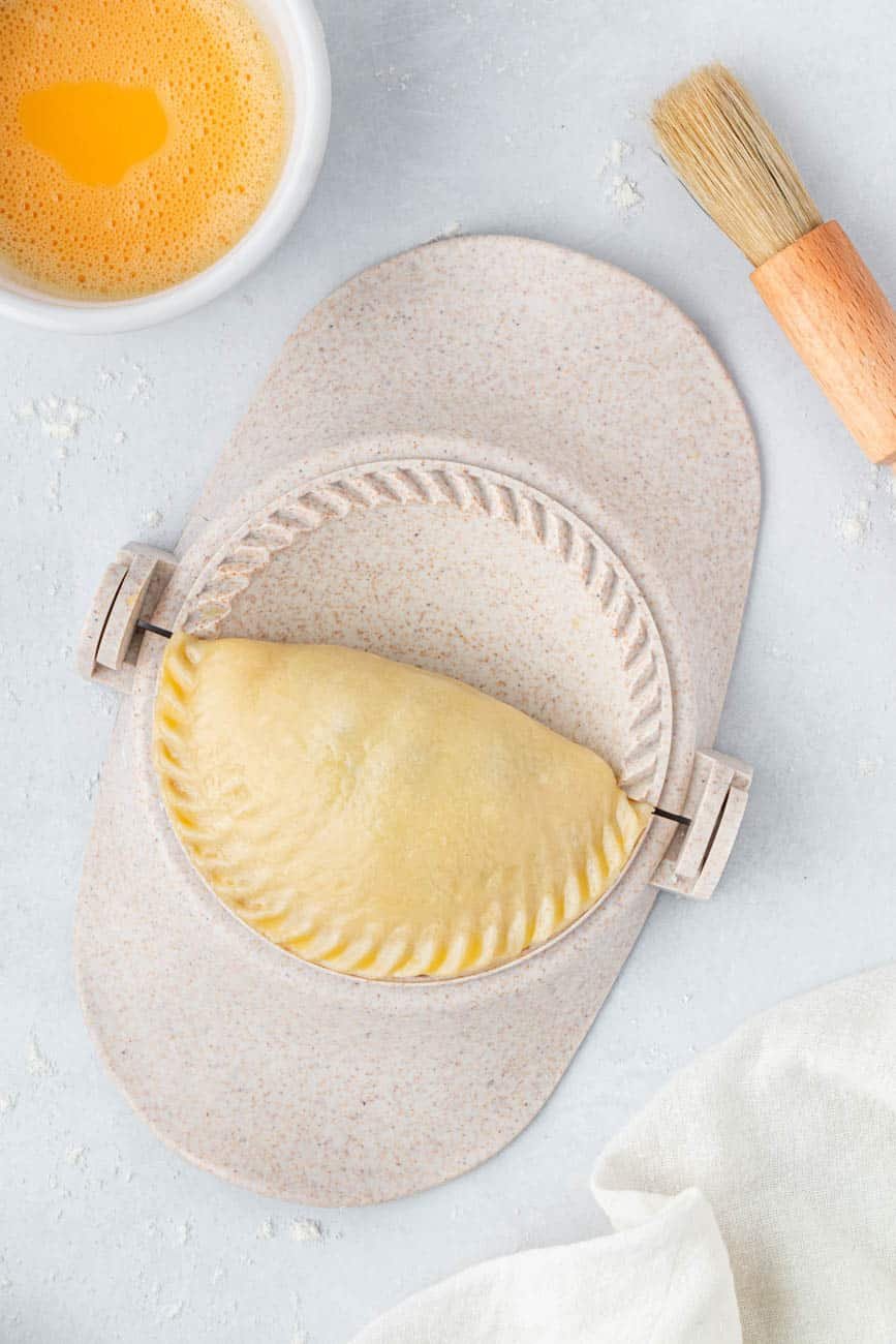 An empanada press with a folded empanada in it.