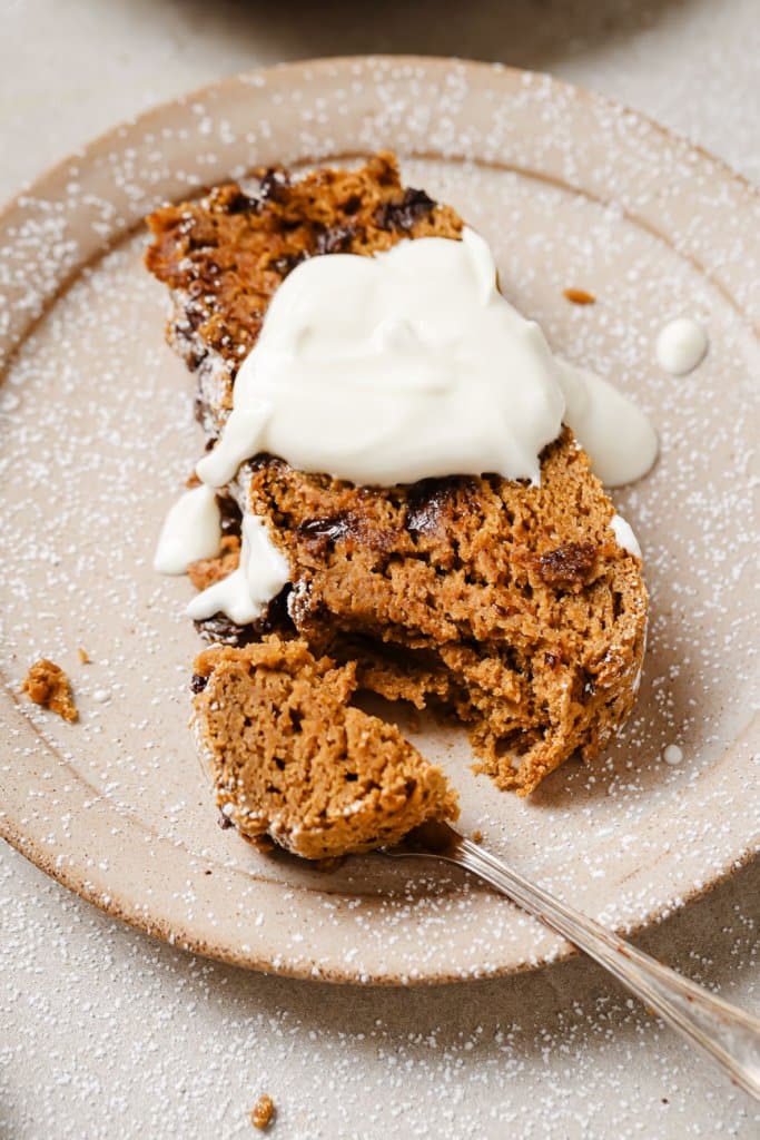 close up of a slice of pumpkin bread with chocolate chips and icing on a plate