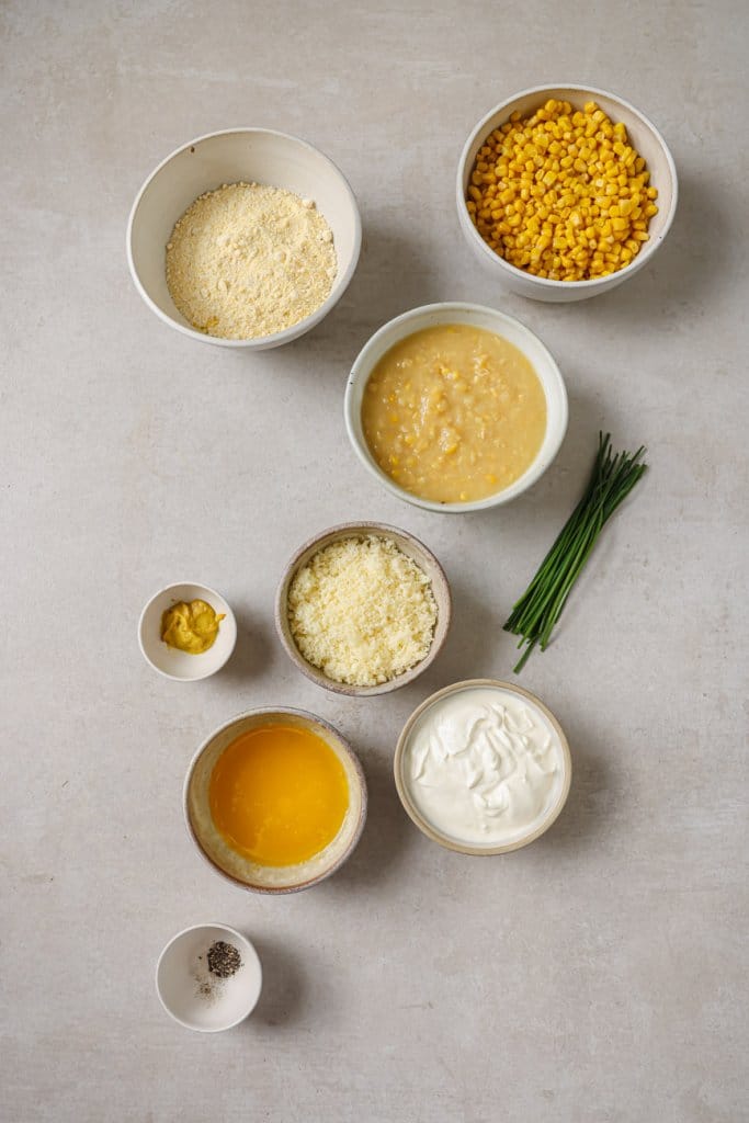 sweet corn, creamed corn, cheese, flour, butter, and chives in small ingredient bowls