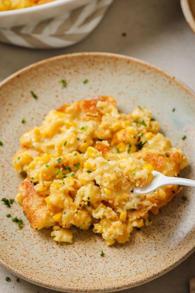 a fork lifting a bite of corn casserole from a plate