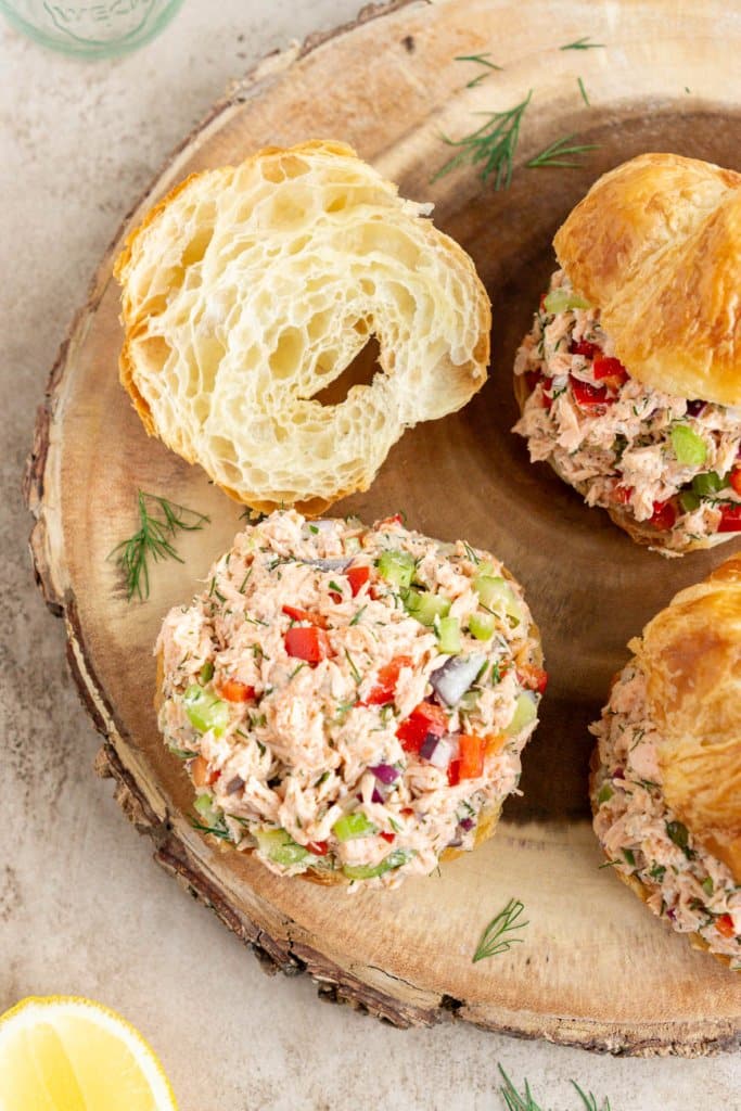 salmon salad sandwiches, open faced on a wood serving board